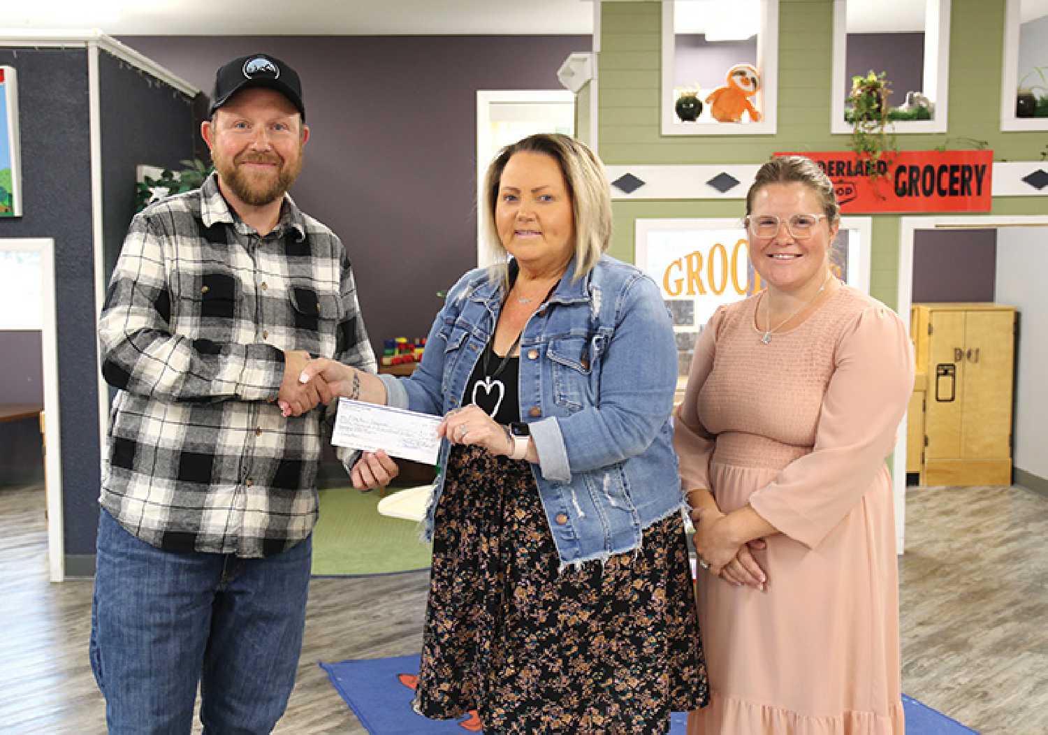 Mike Sidoryk, of the Moosomin Rodeo Committee presenting Terri Low and Sarah Campbell, of Play Fair Daycare with a donation of $12,500.